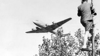 Berliner Luftbrücke: Ein Junge verfolgt von einem Baum aus den Landeanflug eines US-amerikanischen Transportflugzeugs auf den Berliner Flughafen Tempelhof. 