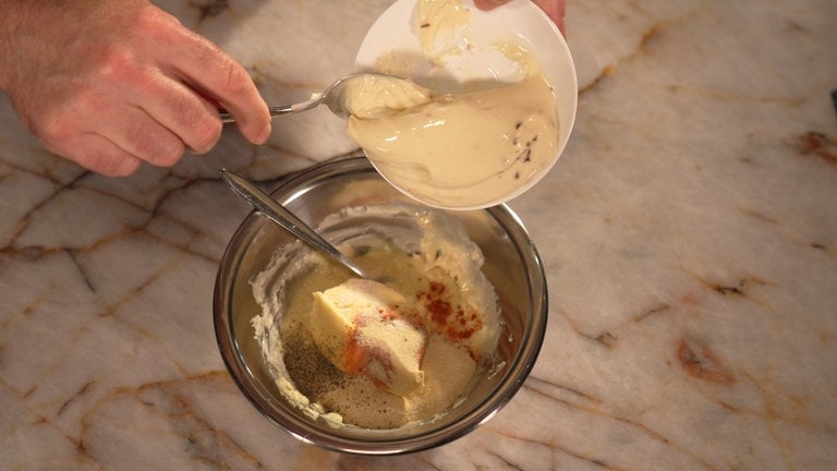 Schmelzkäse, Butter, Zwiebelpulver, Paprika, Salz und Pfeffer zugeben.