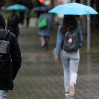 Menschen laufen im Regen durch die Stadt. Für die kommenden Tage erwartet der Deutsche Wetterdienst in Baden-Württemberg Dauerregen. (Symbolbild)