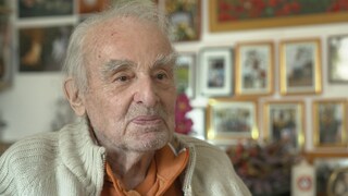 Älterer Mann mit grauen Haaren schaut in die Kamera und lächelt.