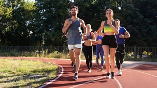 Gruppe von Läufern auf einer Tartanbahn: Laufclubs boomen, immer mehr Menschen trainieren für einen Marathon. Regelmäßiges Laufen stärkt das Herz-Kreislauf-System und hilft, Stress abzubauen – auch ohne extreme Distanz.