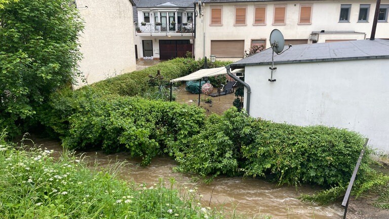 Der kleine Fluss ist über das Ufer getreten. Viele Gärten an denen der Fluss entlangläuft wurden geflutet.