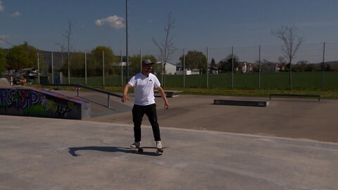 Ein Mann steht auf einem Skateboard in einem Skatepark. Er heißt Adonias de Melo und ist Skate-Lehrer in Tübingen.