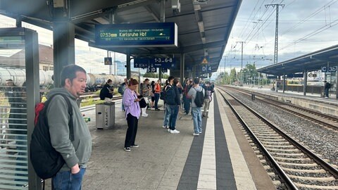 Menschen warten auf dem Bahnsteig: Zugausfälle wegen kurzfristiger Bauarbeiten am Bahnhof Bruchsal.