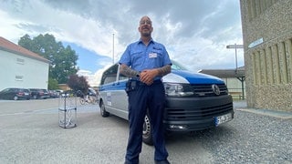 Ein Beamter steht vor einem Polizeiwagen. In der JVA Frankenthal ist Tag der offenen Tür.