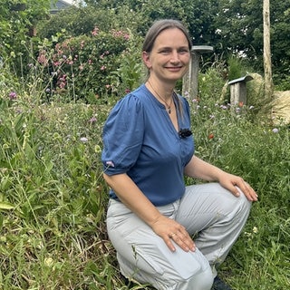 Frau sitzt in einem Wildbienengarten