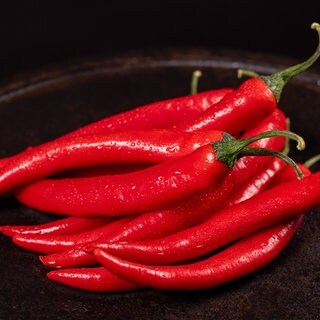 Eine Schala voller Chilis. Möglicherweise könnte ein Wirkstoff aus Chilis gegen Schärfe im Essen helfen.