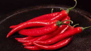 Eine Schala voller Chilis. Möglicherweise könnte ein Wirkstoff aus Chilis gegen Schärfe im Essen helfen.