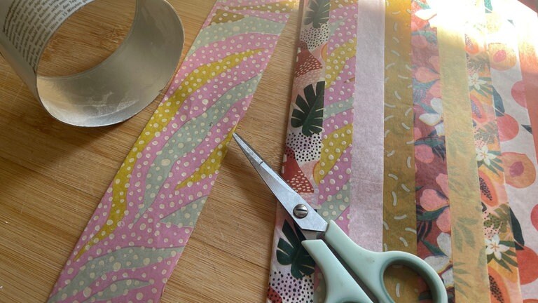 Den Ring außen mit Decoupagekleber bestreichen und mit einem Streifen Decoupagepapier bekleben. Das Papier anschließend mit einer weiteren Schicht Kleber bestreichen und trocknen lassen. 