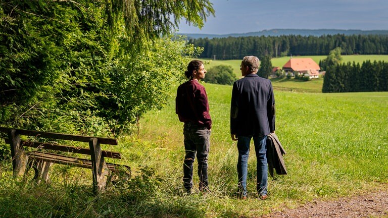Albert (Alessio Hirschkorn) und Bernhard (Karsten Dörr) blicken von der Wiese am Waldrand auf den Fallerhof