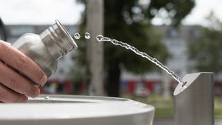 Ein Passant füllt seine Tinkflasche an einem Brunnen, an einer sogenannten «Refill-Station», mit Wasser. 