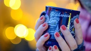 Eine Frau hält auf dem Weihnachtsmarkt eine Tasse mit Glühwein. Insassen der Heilbronner JVA haben jetzt bereits den Glühwein der eigenen Produktion abgefüllt.