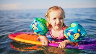 Mädchen mit Schwimmbrett und Schwimmflügeln