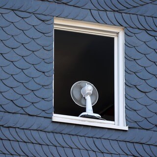 Nach einer sehr warmen Nacht ist ein Fenster in einem Haus am Morgen komplett geöffnet um zu lüften.