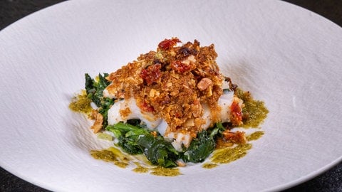 Fisch in Mandelkruste mit Spinat: Die Vorspeise vom Weihnachtsmenü schön angerichtet in einem weißen Teller.