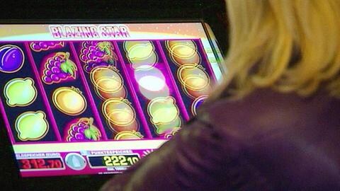 Frau sitzt vor einem Spielautomaten.