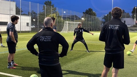 Auf einem Fußballfeld stehen mehrere Spieler in Trikots