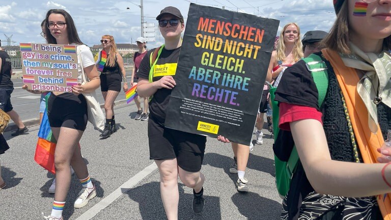 Eine Frau trägt ein Plakat, auf dem sie gleiche Rechte für queere Menschen fordert