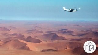 Das ist ein Beispiel·bild. Auf dem Foto ist eine Wüste in Namibia. Rechts oben fliegt ein kleines Flugzeug mit einem Propeller. Rechts unten das SWR Logo für Leichte Sprache.