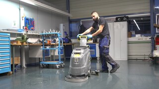 Ein junger Mann schiebt eine Reinigungsmaschine.