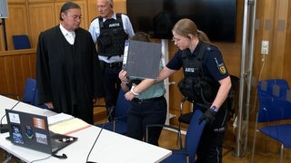 Die Angeklagte wird in den Gerichtssaal geführt und setzt sich neben ihren Verteidiger. Sie war Auszubildende zur Sanitäterin beim DRK, dort soll sie ihre Kollegen vergiftet haben.