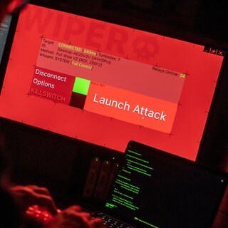 Ein Mann sitzt vor Bildschirmen, die Hacker-Programme zeigen.