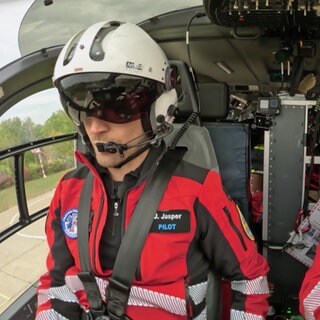 Jederzeit einsatzbereit - Pilot Jens Jasper und Notfallsanitäter Dirk Hornig sitzen im Cockpit eines Hubschraubers und besprechen sich. 
