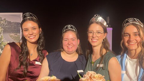 Vier Frauen stehen mit Krone vor einem schwarzen Hintergrund. 