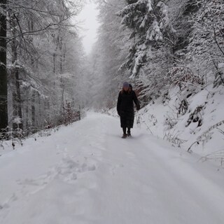Eine Frau läuft durch den Schnee im Wald