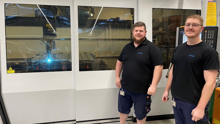 Nils Göltenboth und Bernd Schroff vor einer Laseranlage, die Kühlplatten bearbeitet.