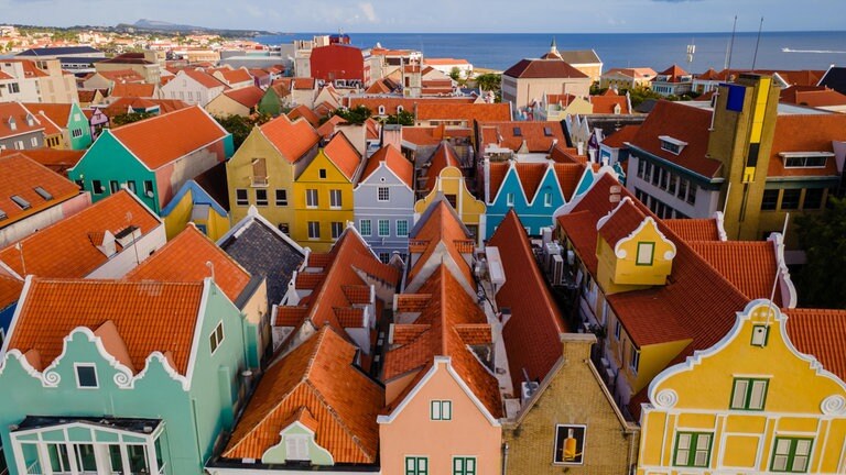 Die malerische Skyline von Willemstad auf Curaçao besticht durch farbenfrohe Gebäude mit roten Ziegeldächern unter einem strahlend blauen Himmel.