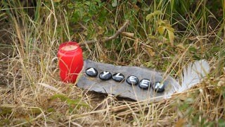 Eine Kerze und der Name "Ayleen" auf einer Wiese.