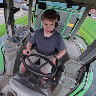 Niklas fährt einen Traktor und trägt ein Headset.
