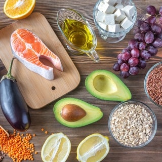 Verschiedene Lebensmittel, die wenig bis kein Cholesterin enthalten liegen auf einem Holztisch.