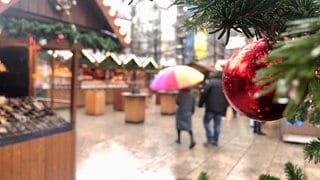 Die Marktbuden haben geöffnet und die ersten Gäste des Weihnachtsmarktes interessieren sich schon für das Angebot. 