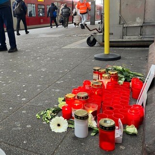 Am Bahnsteig liegen Blumen und stehen Grablichter im Gedenken an den getöteten Zugbegleiter 