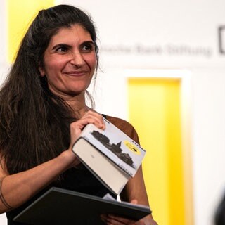 Die Gewinnerin des Deutschen Buchpreises 2026, Shida Bazyar, steht auf der Bühne.