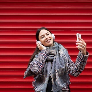 Junge Frau, die mit Kopfhörern tanzt und ein Mobiltelefon in den Händen hält