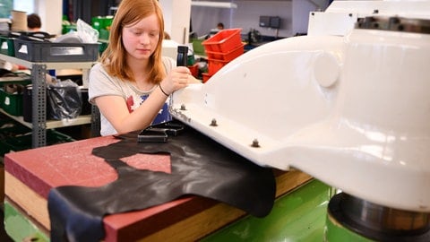 Eine Auszubildene an einer Maschin in einer Schuhfabrik. 