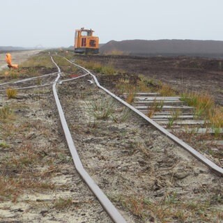 Links und rechts der Gleise warten Kilometer lange Torfmieten auf ihren Abtransport