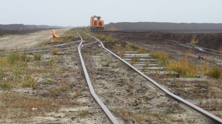 Links und rechts der Gleise warten Kilometer lange Torfmieten auf ihren Abtransport