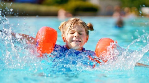 Kleines Mädchen mit Schwimmflügeln planscht im Pool: In den letzten Jahren steigt die Zahl der Grundschüler, die nicht schwimmen können. Die Gründe sind vielfältig.