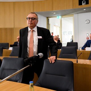 Der ehemalige Landrat des Kreises Ahrweiler Jürgen Pföhler steht in einem Raum an einem Stuhl. Gegen Pföhler wird vermutlich eine Disziplinaranklage wegen Versäumnissen bei der Flutkatastrophe im Ahrtal 2021 erhoben.