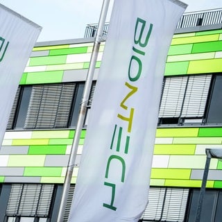 Die Flaggen des Pharma-Unternehmens Biontech flattern vor der Firmenzentrale im Wind.