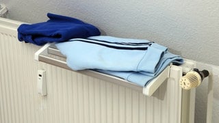 (Symbolbild) Blaue Kleidung liegt auf einem Heizkörper zum trocknen