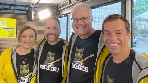 Steffi Stronczyk, Torsten Buschmann, Michael Lueg und Veit Berthold tragen bei der SWR1 Hitparade 2025 in Koblenz das coole SWR1 Hitcat-Shirt.