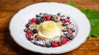 Eis in einem Süppchen mit Beeren auf einem tiefen Teller