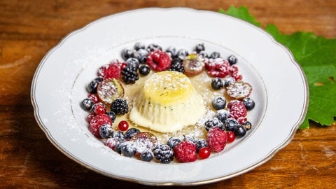 Eis in einem Süppchen mit Beeren auf einem tiefen Teller