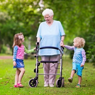 Eine ältere Frau mit Rollator und ihren Enkelkindern im Park