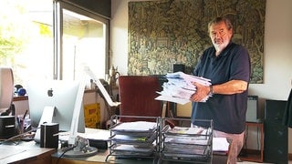 Der Ulmer Arzt Rolf von kenne trägt einen großen Stapel Papiere zu seinem Schreibtisch. Das meiste davon Fallakten, Rechnungen und Briefe der krankenkassen. 